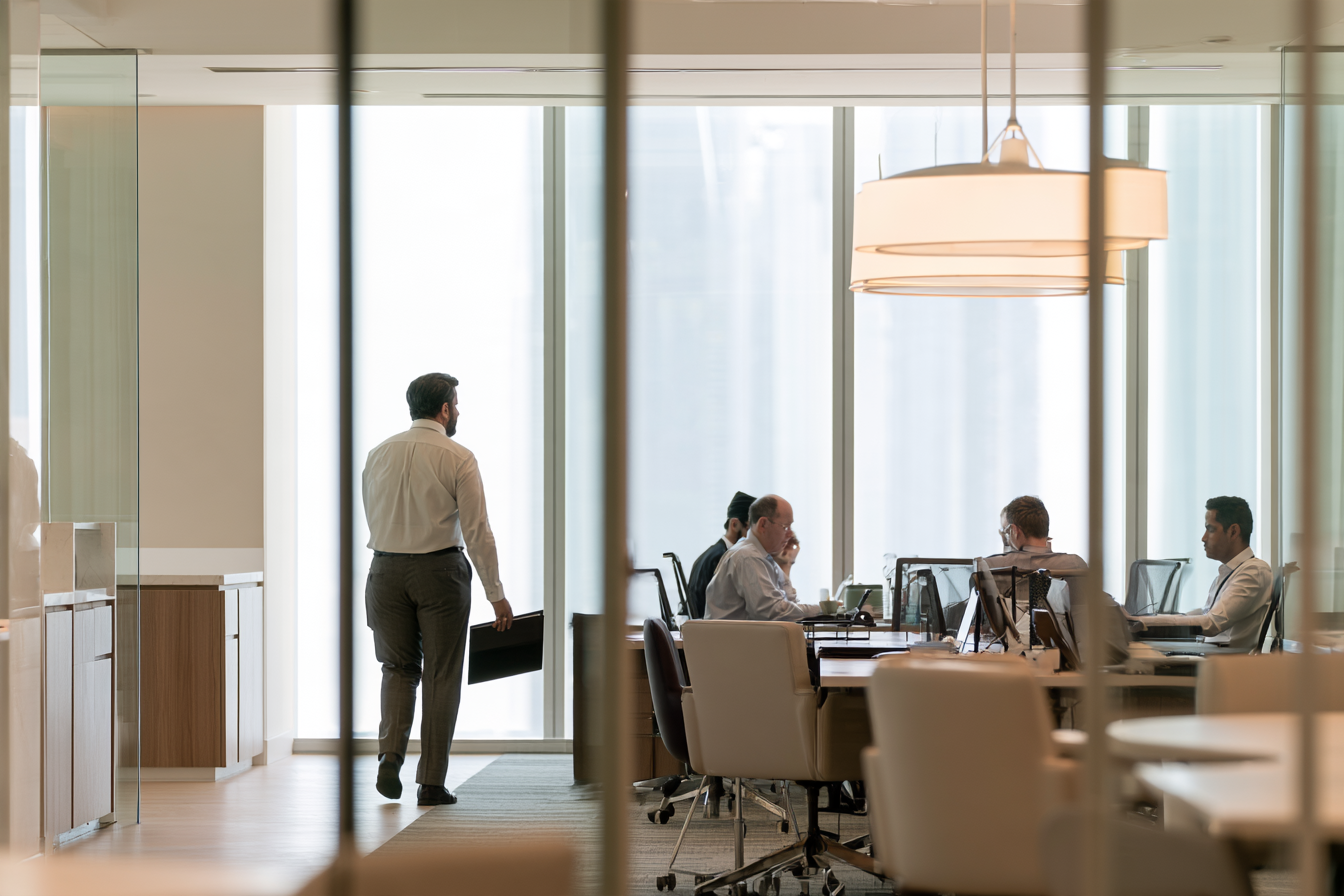 Serviced office with several workstations seen through glass