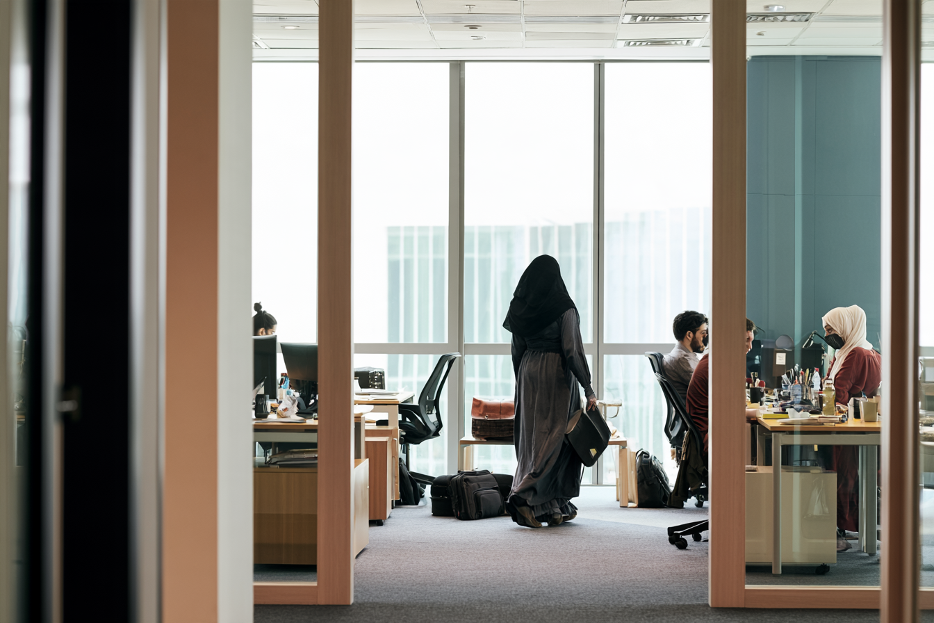 People working at desks in a glass-walled office