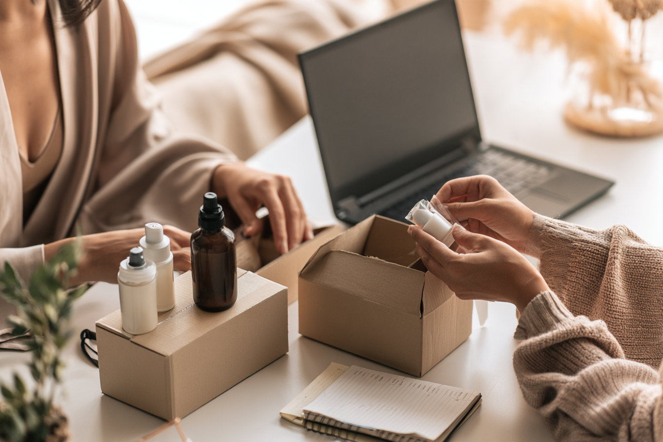 Two people packing small product orders at a desk